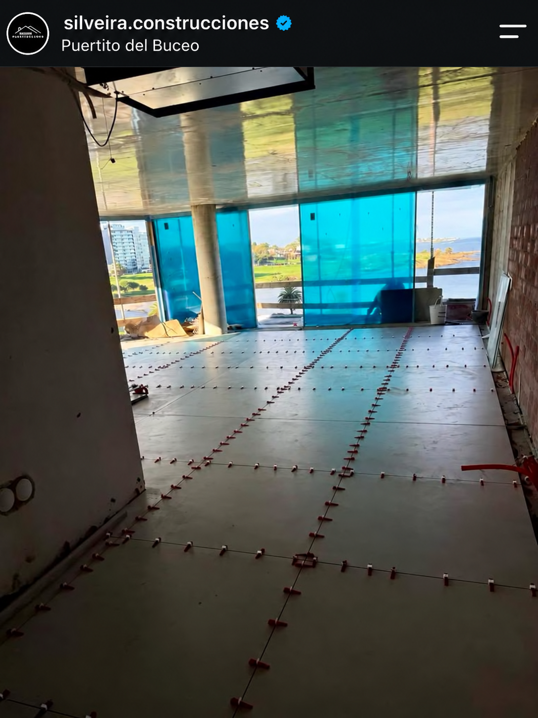 Captura de una publicación del Instagram de Silveira Construcciones: instalación de grandes piezas de porcelanato con niveladores visibles en un ambiente en obras del Edificio Ame.